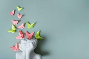 un' figurina di un' testa con farfalle su un' colorato sfondo. mentale Salute concetto. copia spazio foto