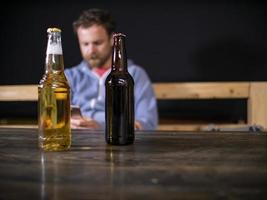 due bottiglie di birra sono in piedi sul tavolo foto