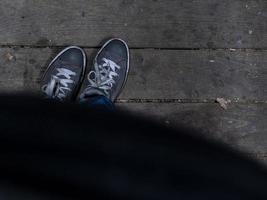 i piedi degli uomini in scarpe da ginnastica stanno sul pavimento di legno foto