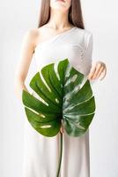 bella donna felice in abiti comodi che tiene una foglia verde di monstera green foto