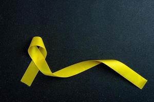 nastro giallo su sfondo colorato. concetto di cancro. foto