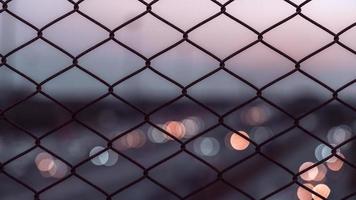 recinzione di collegamento a catena con bokeh chiaro sullo sfondo del tramonto foto