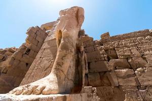 piedi di un'antica statua del faraone nel tempio di Karnak a Luxor foto