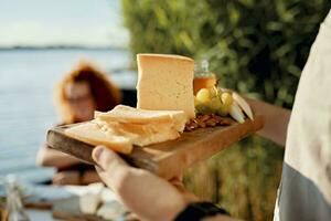 uomo servendo formaggio piatto per amici a un' lago foto