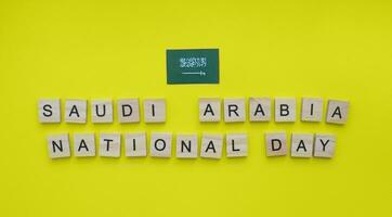 settembre 23, Arabia arabia nazionale giorno, il bandiera di Arabia arabia, un' minimalista bandiera con il iscrizione nel di legno lettere su un' giallo sfondo foto