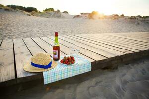 picnic vicino il cappello da mare, vino, occhiali, fragola foto