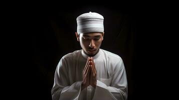 ritratto di giovane musulmano uomo preghiere isolato su nero sfondo foto