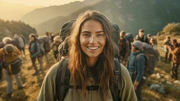 un' sorridente giovane donna escursionista con zaino guardare a telecamera con gruppo di amici escursionisti sorge per il superiore di il collina. escursionista, turista campo. generativo ai foto