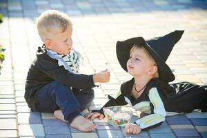 un' ragazzo nel un' scheletro costume feed un' bambino con dolci , Halloween. foto