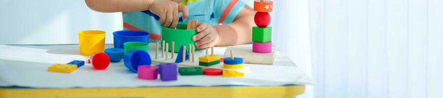 avvicinamento di un' poco ragazzo è mano è giocato con di legno giocattoli. educativo logica giocattoli per bambini. Montessori Giochi per bambino sviluppo. copia spazio. foto