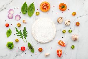 gli ingredienti per la pizza fatta in casa allestiti su sfondo di marmo bianco