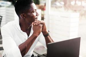 uomo d'affari afroamericano, lavora al computer portatile in un bar, libero professionista foto