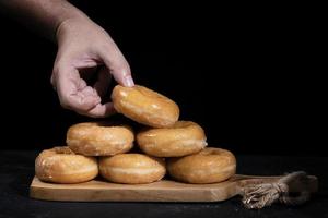 mano che tiene una ciambella di zucchero da una montagna su una tavola di legno foto