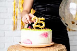 bwoman in abito da festa nero festeggia il suo compleanno tagliando la torta foto