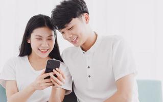 giovane coppia che guarda il telefono insieme a un'espressione felice foto