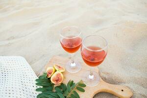 bianca mantello, bicchieri su un' di legno tavola e sabbia. estate picnic avvicinamento foto
