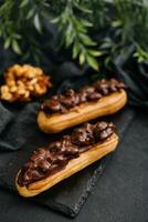 Due eclairs con buio cioccolato su nero tavola foto