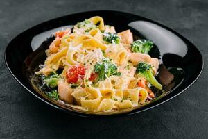 italiano fettuccine Alfredo pasta piatto con grigliato salmone e broccoli foto