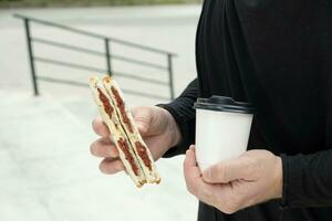 salsiccia Sandwich e cartone caffè tazza modello nel umano mani foto