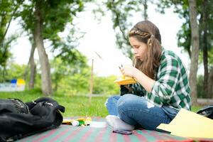 poco ragazza su vacanza nel il parco con il mestiere di fabbricazione un' uccelli becco con carta può uso il tuo dita per mossa il tuo bocca. foto