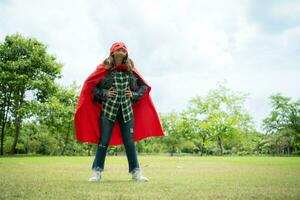 su un' bellissimo giorno nel il parco, un' giovane ragazza gode sua vacanza. giocoso con un' rosso supereroe costume e maschera. foto