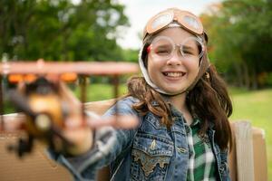 un' poco ragazza su vacanza a il parco con un' pilota attrezzatura e volante attrezzatura. correre in giro e avere divertimento con sua sogni. foto