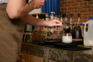 barista preparazione freddo latte macchiato caffè nel caffè negozio, avvicinamento foto