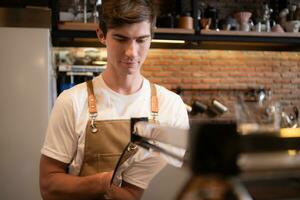 ritratto di un' giovane maschio barista preparazione caffè nel un' caffè negozio foto