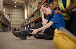 un' magazzino lavoratore console e aiuta un' femmina lavoratore chi grida su nel dolore dopo un' gamba incidente nel un' grande magazzino foto