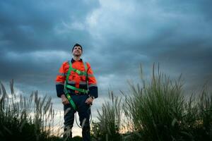 ritratto di un' giovane uomo Lavorando nel vento turbina campo, indossare un' sicurezza veste, il concetto di rilassare tempo dopo opera foto