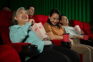 gruppo di asiatico anziano amici Guardando commedia film e ridere a il cinema con Popcorn foto