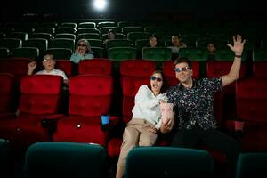 nel un' cinema, un' giovane coppia paio indossare 3d bicchieri orologi film e mangia Popcorn. foto