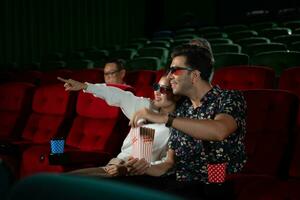 nel un' cinema, un' giovane coppia paio indossare 3d bicchieri orologi film e mangia Popcorn. foto