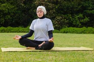 donna attraente in formazione hijab nel parco, meditando. foto