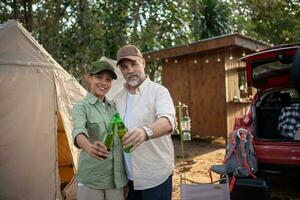 gruppo turisti potabile birra-alcol e giocare chitarra insieme con godere e felicità nel estate mentre campeggio foto