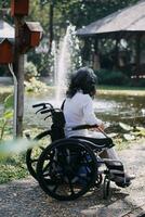 asiatico giovane donna infermiera a assistenza infermieristica casa prendere cura Disabilitato anziano uomo. badante medico servire fisico terapia per più vecchio anziano paziente per esercizio e pratica a piedi su camminatore o canna a Giardino dietro la casa. foto