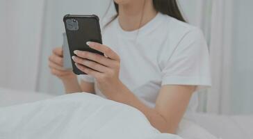 efficiente giovane del Millennio ragazza seduta su un' letto nel il mattina, usi il computer portatile computer e mangia Cornetti e bevande caffè per prima colazione foto