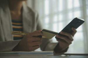 primo piano della mano della donna utilizzando la carta di credito e il computer portatile dello smartphone per l'acquisto di acquisti online foto