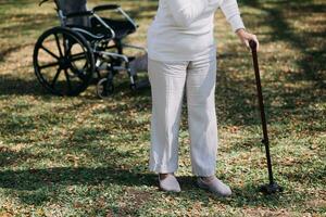 asiatico giovane donna infermiera a assistenza infermieristica casa prendere cura Disabilitato anziano uomo. badante medico servire fisico terapia per più vecchio anziano paziente per esercizio e pratica a piedi su camminatore o canna a Giardino dietro la casa. foto