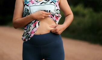 donne corpo Grasso gonfiarsi. obeso donna mano Tenere eccessivo pancia Grasso. dieta stile di vita concetto per ridurre pancia e forma su salutare stomaco muscolo. foto