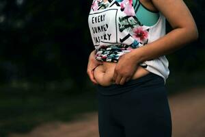 donne corpo Grasso gonfiarsi. obeso donna mano Tenere eccessivo pancia Grasso. dieta stile di vita concetto per ridurre pancia e forma su salutare stomaco muscolo. foto