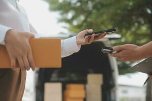 asiatico donna ricevente Prodotto a partire dal consegna uomo a casa, giovane proprietario donna ordine Prodotto a partire dal smartphone applicazione, donna con in linea attività commerciale o pmi concetto. foto