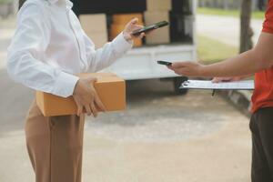 asiatico donna ricevente Prodotto a partire dal consegna uomo a casa, giovane proprietario donna ordine Prodotto a partire dal smartphone applicazione, donna con in linea attività commerciale o pmi concetto. foto