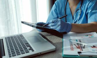 medico Lavorando su il computer portatile computer, scrittura prescrizione appunti con disco informazione carta cartelle su scrivania nel ospedale o clinica, assistenza sanitaria e medico concetto. messa a fuoco su stetoscopio foto