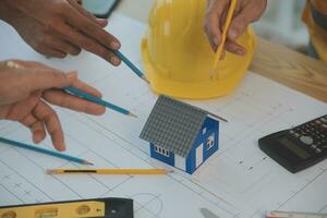 costruzione e struttura concetto di ingegnere o architetto incontro per progetto Lavorando con compagno e ingegneria utensili su modello edificio e planimetria nel Lavorando luogo, contrarre per tutti e due aziende. foto