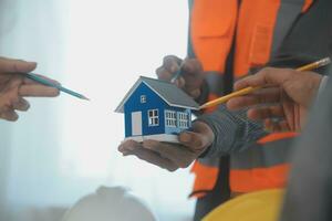 costruzione e struttura concetto di ingegnere o architetto incontro per progetto Lavorando con compagno e ingegneria utensili su modello edificio e planimetria nel Lavorando luogo, contrarre per tutti e due aziende. foto