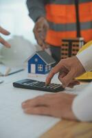 costruzione e struttura concetto di ingegnere o architetto incontro per progetto Lavorando con compagno e ingegneria utensili su modello edificio e planimetria nel Lavorando luogo, contrarre per tutti e due aziende. foto