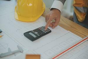 costruzione e struttura concetto di ingegnere o architetto incontro per progetto Lavorando con compagno e ingegneria utensili su modello edificio e planimetria nel Lavorando luogo, contrarre per tutti e due aziende. foto