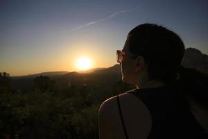 donna che si gode un bellissimo e colorato tramonto su una montagna del deserto foto