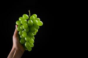 mano Tenere verde uva mazzo isolato su nero sfondo con copia spazio. ai generato foto